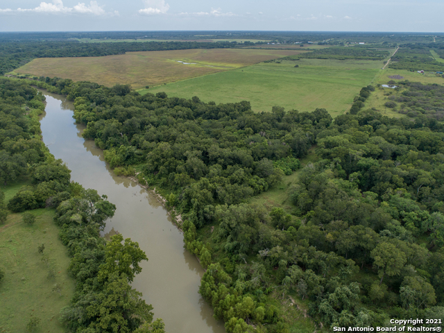 Optimal hunting and ag land just south of Cuero with plenty of live water and live oaks. Located on the Guadalupe River with 1,400 feet of frontage, this ranch has 7 water wells, electricity, a hunting cabin, improved pastures, and is currently home to cattle and various wildlife year-round. The water access, protective brush and trees, and plentiful food sources attract scores of whitetail deer, wild turkey, and hogs. Additionally, the river bottom provides a great place to catch catfish, bass, and the occasional alligator gar, while the ponds are an ambush spot for the waves of dove that cross between the food and water sources every morning and evening. If you are looking for a property to fish, hunt, raise cattle, or if you just want a great view, this is it! Approximately 40% open space/pasture and 60% wooded with over 100 feet of elevation change in the two-mile stretch from one side of the property to the other. A 45-acre coastal Bermuda hay field provides 100 round bales per cut, and a small sand and gravel pit can be used for additional income or material for road repair. There is a small pond and several seasonal creeks throughout the property. About 50% of the land is in the 100-year flood plain exhibiting very fertile river bottom soil, sand, and rock deposits. Easements include two transmission lines, two pipelines, and three neighbors' road access. This low-fenced property comes with a small trailer-style hunting cabin with water well, electricity, and septic. There are an additional six drilled water wells in various conditions from a fallen down antique windmill to a fully functioning electric pressure pump. The cattle guard entrance leads to a partially paved and partially gravel road that continues throughout the ranch. A large set of pipe cattle pens with lumber backing is in the center of the property. Some mineral rights are negotiable. Agricultural tax valuation.