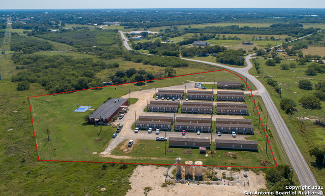 This oilfield housing property on 7.82 acres is located just outside of Cuero on FM 766. There are currently 104 rooms in operation providing lodging for the oilfield workers in the Eagleford Shale. This property is very popular with several oilfield companies and provides guests with food and housing as needed. As the oil and gas prices continue to rise, this income-producing property potentially stands to benefit into the future. Built in 2014, this compound consists of 20 - 18x76 ft. lodge buildings with 5 rooms per building. Each studio room has its own bed, recliner, bathroom, closet, TV, and wireless internet. There is also a separate office building, and a larger dining facility with a lounge area, open dining room, laundry rooms, office space, workout room, and a state-of-the-art commercial kitchen with all the necessary equipment to feed large quantities of people. A lighted basketball court is located behind the dining hall. The site was originally designed for 170 rooms and has the infrastructure in place to add more rooms or even RVs for additional income. Utilities include City of Cuero water and sewer for all buildings. The property is high fenced along the perimeter and has a security gate at the entrance. 7.82 acres of level land with no floodplain and 800 feet of FM 766 road frontage. A large, manicured yard with several live oak trees wraps around the side and back of the property. Other trees include mesquites along the perimeter and crepe myrtles near the buildings.