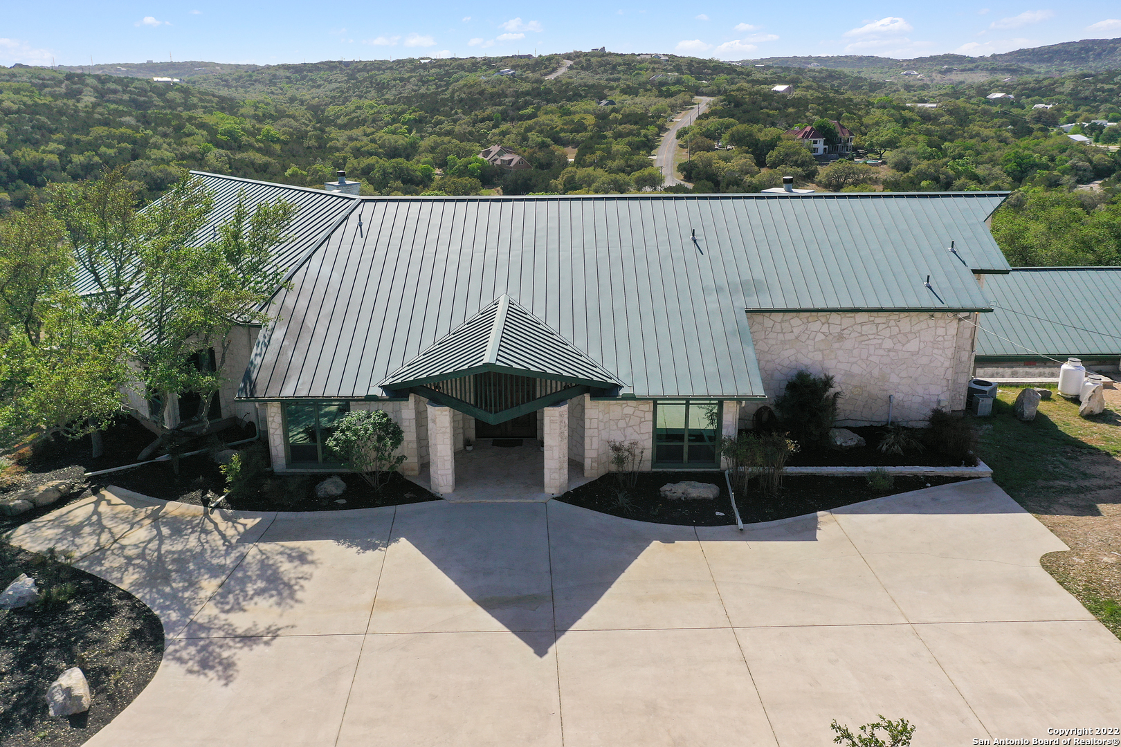 This gorgeous estate sits on approximately 11.68 acres and offers stunning views of the Texas hill country. Custom built, this home showcases spectacular interior details and has been meticulously maintained. Upon arrival, an extended driveway guides you to the entrance and additional parking. Curb appeal is a given with delicate landscaping, greenery, and a stone exterior. Inside, soaring ceilings are highlighted by wooden details, picture windows, and stone accents. A grand entrance guides you to the formal living space with access to the balcony, which overlooks mature shade trees and Texas blue skies. A designated dining space across the way makes for elegant entertaining with custom cabinetry fit for a bar area or China display. In the casual living area, postcard-perfect views can be enjoyed from the interior with a cozy stone fireplace. This quaint space provides peace and tranquility, perfect for spending time with loved ones. The household chef will appreciate the gourmet eat-in kitchen. The kitchen comes equipped with all-white cabinetry, complementing granite counters, backsplash, stainless steel appliances, a gas range cooktop, and an industrial-like vent hood. Office space can be found off the entrance and offers French doors for added privacy. Retreat to the luxurious-sized primary showcasing vaulted ceilings, wood flooring, fireplace, and reading nook. The spa-like en suite has dual sinks with an elongated vanity, walk-in shower, and jacuzzi tub. The walk-in closet was built for a shopaholic and for additional storage. Three spacious secondary bedrooms, three baths, 2 half baths, and a generous game room with a bar conclude the interior. A detached, two-story apartment includes separate quarters, with dedicated entrances for each. A full bed and bath can be found upstairs, and the second bed and bath are located in the downstairs quarters. Outside, a covered patio overlooks the stone surrounded by an infinity pool. An outdoor powder bath adds convenience when cooling off during the summer season. A pergola is ideal for resting from the sun's rays. A one-of-a-kind pavilion can be found on the property spanning over 2400 sqft. A fireplace, custom barbecue pit, and a bar add endless possibilities for entertaining! With no near neighbors' insight, this exquisite property is not one to pass up on!