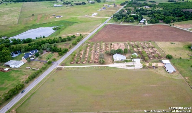 This charming and meticulously cared for 10-acre country estate in the La Vernia school district features a 2752 sq ft home set amongst a mature pecan tree orchard, fruit trees and established oak trees.  The 3br/3ba house is flanked by a large vegetable garden and coastal field.  Sidewalks provide access to the home, detached office, detached garage with RV hookups, and the orchard.  The property features a 2728 sq ft shop/tractor barn/equipment shed, and a 1092 sq ft RV shed complete with a second 50-amp RV hookup.  The detached garage is equipped with a kitchen and full bathroom offering potential for future conversion to a guest house. The property is accessible via a private electric gate off of FM 775 and has 6-wire electric fencing on the perimeter of all 10 acres and cross fences.  Check out the list of improvements below and schedule your appointment to see this beautiful property!    2752 sf Home:  A 650 sf front porch, and 825sf family room, a rock fireplace with gas burning logs, and a 304 sf covered patio make for a great gathering place.  Custom solid oak cabinetry is featured throughout with quartz countertops in the kitchen.  Flooring was updated in 2011 with ceramic tile throughout and new carpet in the master bedroom.  Both HVAC units with heat pumps were updated in 2012: 1-unit for the family room and the second unit for the rest of the house.  The roof was replaced in 2016 with standing seam metal.  The home is wired for security, has programmable thermostats, solar screens, and gutters.    Detached Garage:  This 864 sf cedar siding structure with wall to wall wood shelves could easily be converted to a Casita.  It is equipped with a 170 sf kitchen featuring ceramic tile floors, custom white cabinets, laminate countertopd, an electric stove, a stainless-steel sink, and a 54 sf full bathroom.  An AC window unit, electric wall heater and solar screens aid in climate control.  The roof was updated in 2016 to standing seam metal.  There is a concrete pad outside of the garage for parking and 50-amp RV.     Detached Office:  This 480 sf frame structure with cedar siding, concrete slab foundation, and standing seam metal roof (updated in 2016) has french doors opening onto a 240sf covered porch.  A kitchenette with custom cabinets, laminate countertops, stainless-steel sink, ceramic tile floors, AC window unit, electric wall heater, fluorescent overhead lights and solar screens make for a delightful workspace.    Shop:  The 1225 sf insulated shop with concrete floors and insulated finished interior walls and over-head flourescent lighting was built as a carpenter shop with designated outlets and switches for a variety of saws, planers, and sanders.  The center peak of the building is 12' high.  Walls are 10'4" high and are constructed off 29-guage metal.  The roof is 26-guage metal.  Three 36"x80" doors and two 8'x10' sliding barn doors provide access to the shop and connect it to the tractor shed, equipment shed, and RV shed.  The shop is heated by a cast iron wood burning stove.  Cabinetry with a stain-less steel sink provides a place to clean up after the chores are done.    Tractor Barn:  This 943 sf barn has concrete floors and overhead lights.  Walls are 29-guage metal, roof is 26-guage metal.  The two 12'x12' sliding barn doors provide ample access for storing a variety of equipment and vehicles.    Equipment shed:  This shed is 560sf with an earthen floor providing future conversion to horse or livestock stalls.  29-guage metal walls, 26-guage metal roof and shed has electricity.    RV shed:  This shed is 1092 sf with a gravel floor, a 14' high ceiling and a 50-amp RV hookup.      Green house:  This 60sf frame structure with cedar siding, a concrete slab foundation, galvanized metal roof, and electricity was used to prepare seedlings to plant in the vegetable garden.  It has the potential for multiple used.  Orchard:  All pecan and fruit trees are irrigated with a drip system from a private well.