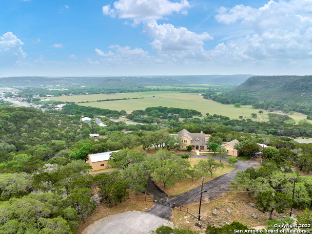 YOUR SEARCH IS OVER! This RARE find is just what you've been looking for. Located on a quiet, private culdesac, with  7+ UNRESTRICTED acres, No HOA and the most Stunning Hill Country views!!! Live your best lake life in the Texas Hill Country. Sit back and enjoy the beautiful in ground pool, overlooking the most gorgeous views or just sit back on the deck and entertain friends and family. There is always a nice breeze while enjoying the outdoor views and watching the wildlife. Jump on your ATV and travel the property on accessible roads and paths, which also leads to a back entrance and access to Old Sattler Road. Enjoy fishing, swimming, paddle boating in your own pond, all right in the backyard! So much for everyone to enjoy.  An additional story and a half guest quarters with kitchen, bathroom, living area and nice size upstairs loft give you plenty of added space for entertaining friends and family. Use this extra space for an office, exercise room, game room or whatever you choose. There is plenty of storage with a nice, large, 2 level, 50 X 30 workshop to keep all your lake toys, boat, jet skis, atv's, etc. to better enjoy beautiful Canyon Lake. Boat ramp 1 is approximately a mile away and always open. The Guadalupe River and Whitewater Amphitheater are a short distance as well. Large green house, dog kennels, many extras. Call to see today!