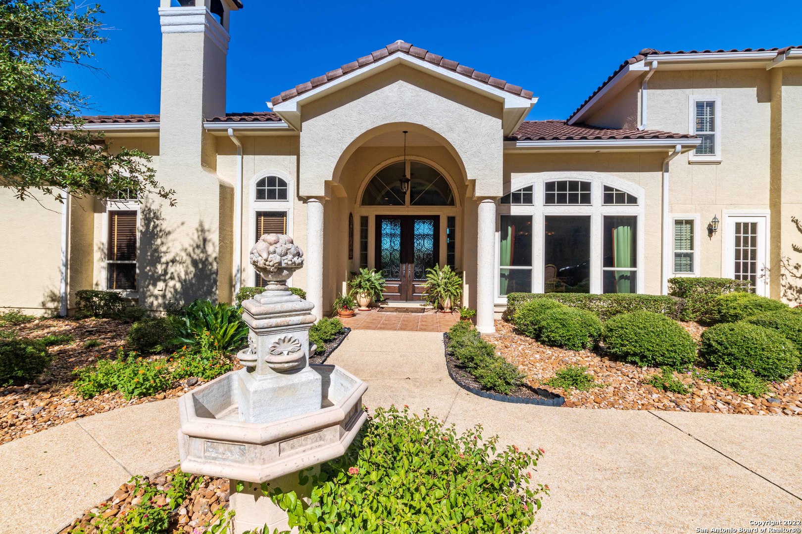 As you enter the grounds of this 1.5-acre estate, in the heart of the prestigious Tapatio Springs golf community, you feel the quality and privacy of the home you are about to tour. Immediately after entering the home, you will notice the custom details that abound throughout this estate. As much as you desire to tour the home, the view will draw you out to the stunning hill country, golf course, seasonal creek and resort views off of the large covered patio. After catching your breath, the tour begins with a well-appointed great room that includes cased windows, stair stepped ceilings with recessed lighting, Roman columns, niches with puck lights, travertine floors, gas log fireplace and more! Most features in this room are continued throughout the rooms in this extremely detailed home. The gourmet kitchen will impress the best of chefs, with commercial style gas cook top, complete with grill and griddle, double ovens, warming drawer, appliance garage, vegetable sink with disposal, endless custom cabinet features, under cabinet lighting, built in Thermador refrigerator, plenty of counter space, huge walk-in pantry and natural light abounds. As you leave the kitchen to enter the dining room, there is a butler pantry along with a dry bar, stemware storage, wine chiller and beverage prep area.  The dining room itself has beautiful ceiling details and lighting that can be set for any mood desired. The luxurious media room features custom, hardwood cabinets, another gas fireplace, surround sound entertainment center, with components that provide stereo throughout the house, when desired. The ceilings in this room feature cove lighting that projects the perfect amount of light when enjoying movies. The owner's suite features two large closets, coffered ceiling, built in cabinets with lots of storage, large windows overlooking the majestic views and access to the patio and entertainment areas. The ensuite bath features separate vanities, garden tub, large shower with multiple shower heads, built in drawers, cabinets and hamper, along with gorgeous tile details throughout. The adjoining exercise room features not only plenty of space for work outs but also has a full, true sauna. The office is breathtaking with cherry wood cabinets, built in bookcases and desk, complete with more long distance, stunning views! The upstairs bedrooms each have their own bathroom and large walk-in closets. In addition to the upstairs bedrooms, there is a flex room that would make a wonderful game room or could be converted in to another, secondary suite with full bath. The laundry room features plenty of storage, counter space for folding, extra refrigerator and a wash basin. Other features include two powder rooms, a central vac, an oversized, three car garage with an abundance of storage, including more custom cabinets, storage closets, etc. Exterior lighting, bocce ball court, plenty of guest parking areas, curbed driveways and lighted limestone cut walls will take your breath away at night. Wrought iron fencing, sprinkler system, built in security system and more.