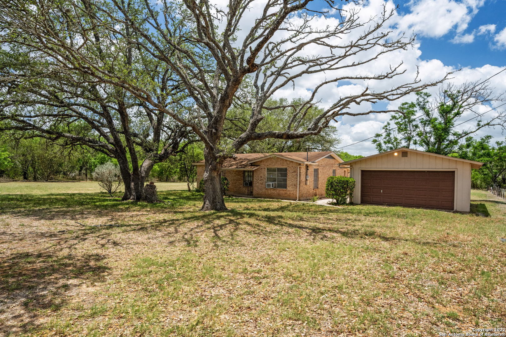 Location, location! Over 1 acre on Loop 1604 South! Country living in San Antonio! Charming 2 bedroom, 1.5 bath brick home with a 2 car detached garage with a large man-cave attached! Bring your trailers for plenty of parking! NO RESTRICTIONS!