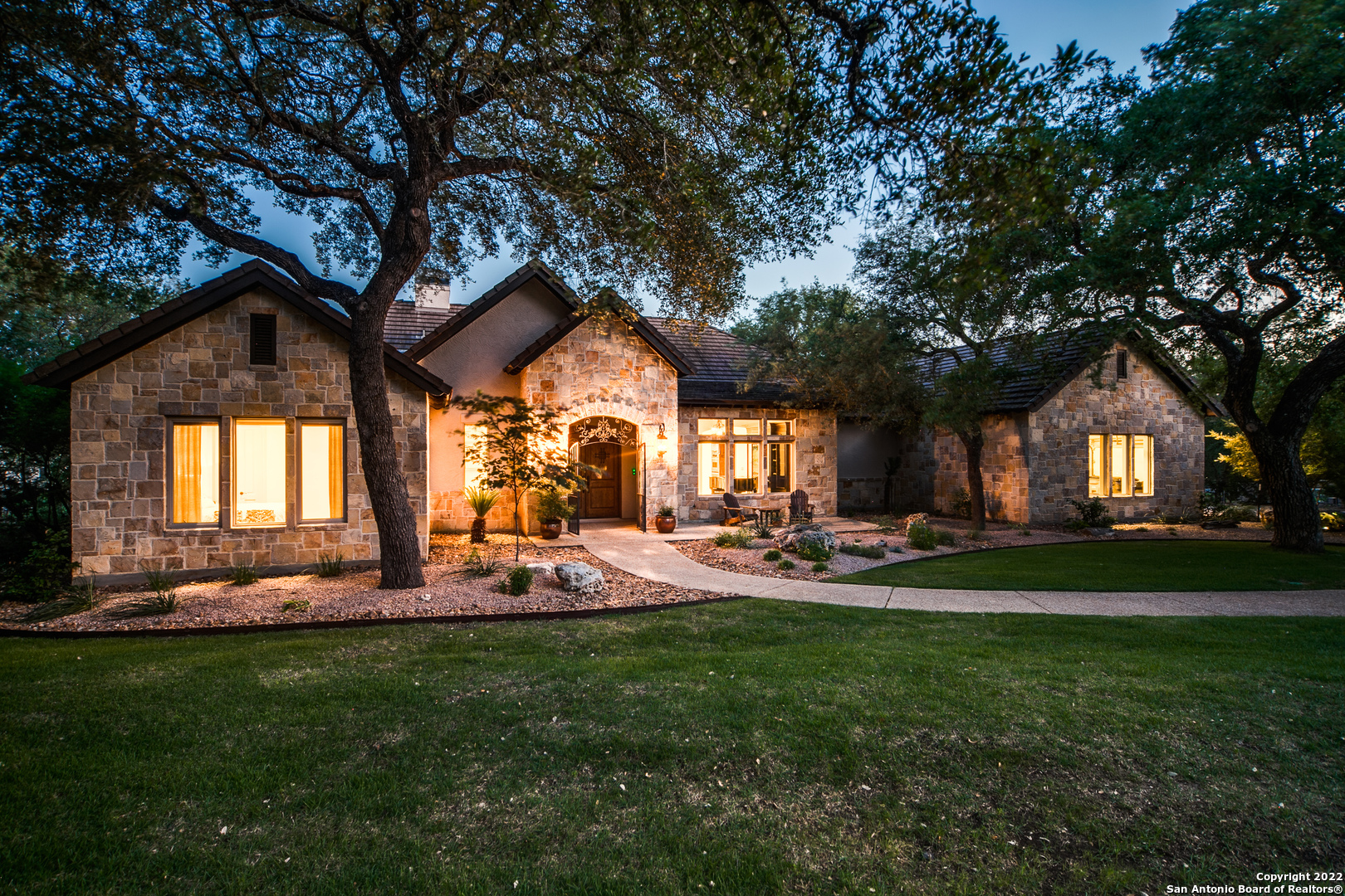 Find an escape from the hustle and bustle of the city with this gorgeous Hill Country gem. Nestled on an expansive lot with a bluff view and mature trees, this stunning countryside retreat's stone and stucco exterior opens to reveal a stately interior filled with quality craftsmanship. Rustic charm is found throughout the home's open floor plan in the form of high ceilings with exposed wood beams, tile and hardwood floors, arched doorways and exquisite mouldings. Located next to the grand double door entry is the formal dining room. The spacious family room features a patio access, surround sound wiring and a stone fireplace that extends to the crest of the cathedral ceiling. Take your culinary abilities to new heights in the spacious island kitchen, complete with granite counters, tile backsplash with a mosaic centerpiece, stainless steel appliances, a casual dining nook with bow windows and pendant lighting suspended over an eat-in breakfast bar. Boasting a tray ceiling, bow windows and a walk-in closet, the relaxing primary suite exudes an aura of refined elegance. Equipped with dual vanities, an inset whirlpool tub and separate shower, the primary en suite bath is perfect for melting away stress after a long day. Other distinguishing features include a private office and reading room with French doors and custom built-ins, as well as well-appointed secondary bedrooms. Just behind the home is an incredible outdoor paradise, which contains a covered patio with an outdoor fireplace, summer kitchen and patio speaker wiring, a Keith Zars pool and waterfall, plenty of mature trees and a detached Casita of 720SF, which includes a large living area, and an additional bedroom and bath. With the casita this house is a total of 4428SF priced at $375/SF. Whole house generator ($26,000) installed in 2021. Social country club membership is available.