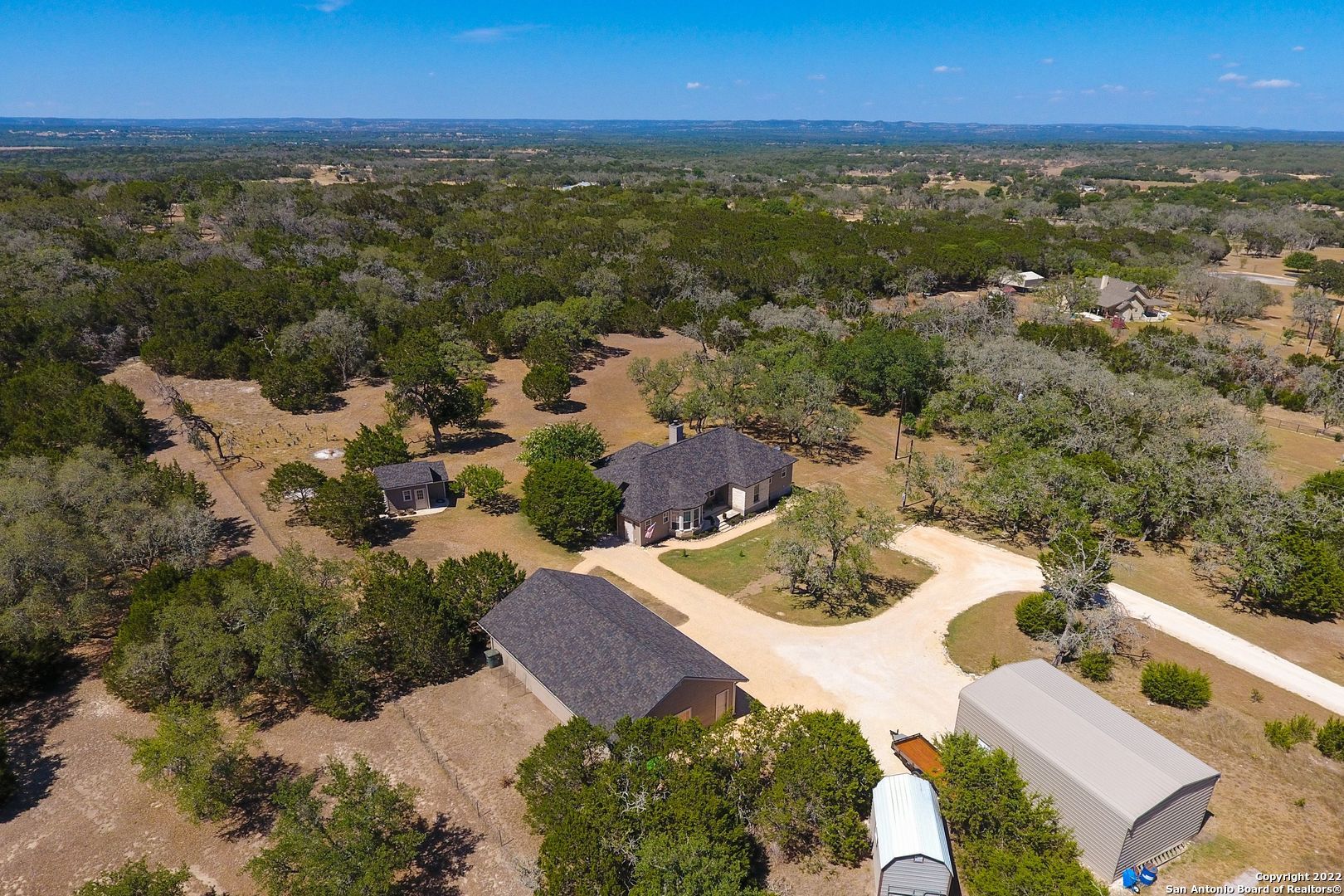 Enjoy 5 private acres in the Texas Hill Country.  2200 sqft 3BD/2 1/2 bath (new roof).  Detached 28 x 48 3 car garage, including a semi-finished in-law, guest quarters approx 400 sqft . 23x 35 sqft RV GARAGE 12 ft remote door with 70-amp power, room for toys and more.  Matching pump house with 2500-gallon storage tank including Pelican water treatment system offering 15 + gal per minute water pressure.  2021 remodeled kitchen boasts new energy efficient appliances with large deep sink and easily accessible storage pantry.  Semi-open floorplan for indoor/outdoor entertaining. Utility/mud room, new 50-gal water heater. HVAC has a transferable waranty. Expansive park-like backyard with room for custom pool, greenhouse, raised garden or barn for horses.  See the sparkling stars in the dark skies neighborhood.
