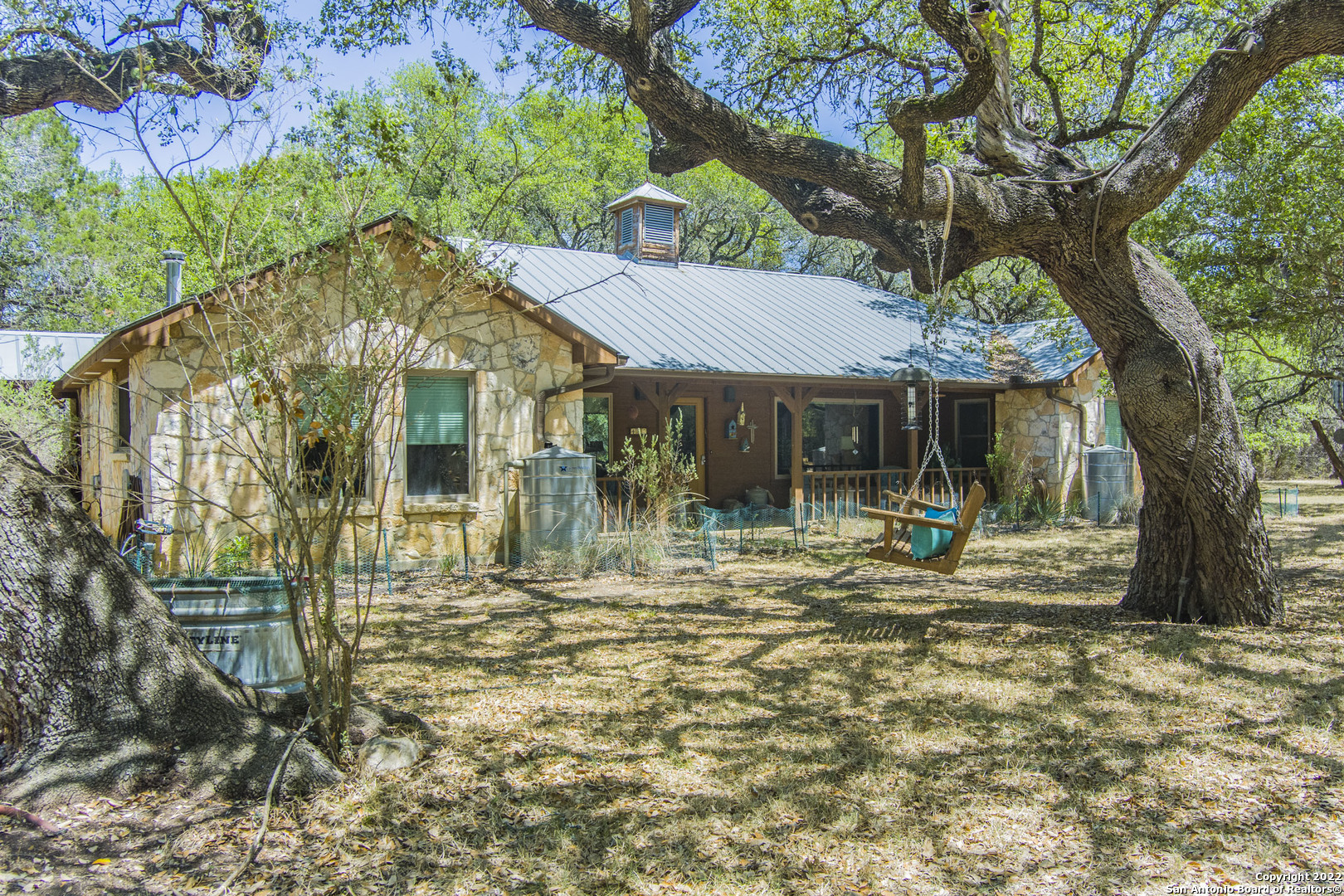 A Texas Hill Country Nature Lover's Paradise!  This lovely home on 6.07 wooded acres awaits you in Bulverde Tx.  A friendly Mermaid will greet you as you drive up to the house down a wandering road through the trees.  Upon entering the house you'll find the Living Room filled with light due to the Huge Picture Window that looks out on the back yard's massive Oak Trees. All windows are super energy efficient which helps for low electric bills.  The Island Kitchen and Utility Room both have an abundance of storage.  The Primary Bedroom brings nature indoors with it's large picture windows.  All 3 bedrooms are oversized and have large closets.  A Wooden Deck stretches across the back of the house and is perfect for BBQs or for sitting out in the evenings and watching deer, hummingbirds and other wildlife in the yard. A fully fenced garden area with 2 keyhole raised garden beds and rain catchment setup to water with. Two, free standing wood burning stoves to take the nip off of a cool night are in the living room and master bedroom for your comfort. A Boardwalk extends from the deck and takes you to two large, wonderful Workshops, one complete with air conditioning - A Crafter's Paradise!  This cozy home invites you to escape the city and come and live in the woods.