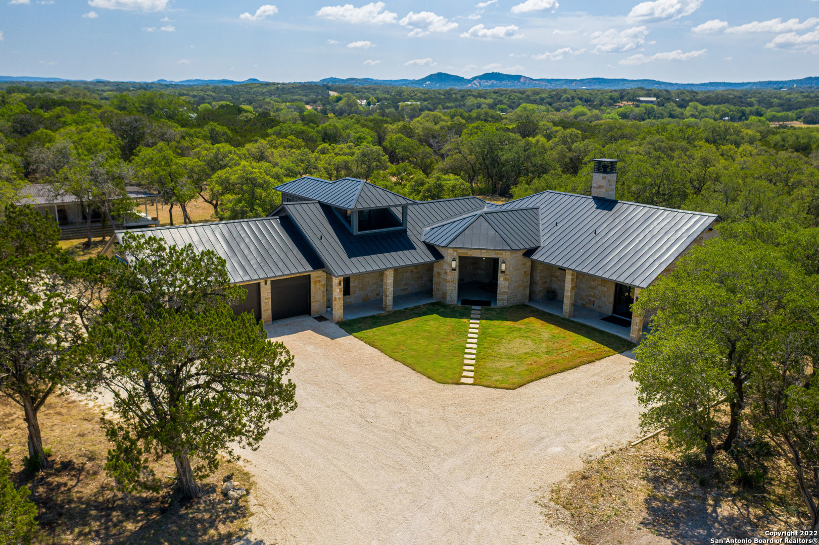 Welcome to Boot Ranch, located in the great Texas hill county.  This parcel of land is a diamond in the rough! It is hard to find this amount of land with as much flat terrain in the hill country as this parcel offers you.  The land has been cleared to highlight the countless oak and cedar trees on the property that provide ample shade and privacy.   The home was custom built and has been planned for everything you may want. If you desire attention to detail, exquisite upgrades, and the feel of luxury in your home, look no further.  Enjoy all of the natural light throughout the home with all the large custom windows and doors.  The front and back doors are custom built and cost over $12,000 each.  The master bedroom features a large spacious sleeping area highlighted by two separate bathrooms and large walk in closets.  The bathroom to the left features a large walk in shower and is pre-plumbed for a steam machine.  The bathroom to the right features a large soaking tub.  Countertops throughout the home are leathered granite which further highlights the exquisite detail brought into the home.  The first island in the kitchen is capped with striated marble with waterfall sides.  Each secondary bedroom has their own full bathroom with large closets.  Before you make your way upstairs you will find the family room.  The door in the back of the room will take you to a hidden room that you can turn into a safe room, gun room, or more.  The barn door for the family room is over 100 years old and was actually the front door of an old church in Comfort.  It was saved from being destroyed before the church was torn down.  As you make your way upstairs to a tranquility room which is great for yoga, working out, and more, you will find your own private balcony that overlooks the property.  While enjoying the outdoors, keep an eye out for deer, wild peacocks, and other native wildlife.  When it is time to get closer to nature, you can relax on the oversized back covered patio.  This patio is also pre plumbed and wired for an outdoor kitchen and speaker system.  The three car garage features ample space for your vehicles and outdoor toys.  It is pre plumbed for a water softener and an in home vacuum system.    As you stroll through the property make sure you find your way down to the creek bed. Down there you will find a picnic table where you can eat your lunch while shooting your pistol and rifles at the targets that are set up.  When water runs through the creek you can sit there and watch the waterfalls cascade off of the rock formations.  There is also an 18 ft hole that makes for a perfect swimming pool. The creek photos provided were taken two years ago when water was running through the creek. The property is fenced on all four sides and features two gates to access the property.  Nearly all of the fence has the high game fencing, only a small section is barbwire.  If you are looking for a wonderful home, privacy, luxury, and a desire to connect with nature, this home is what you need.