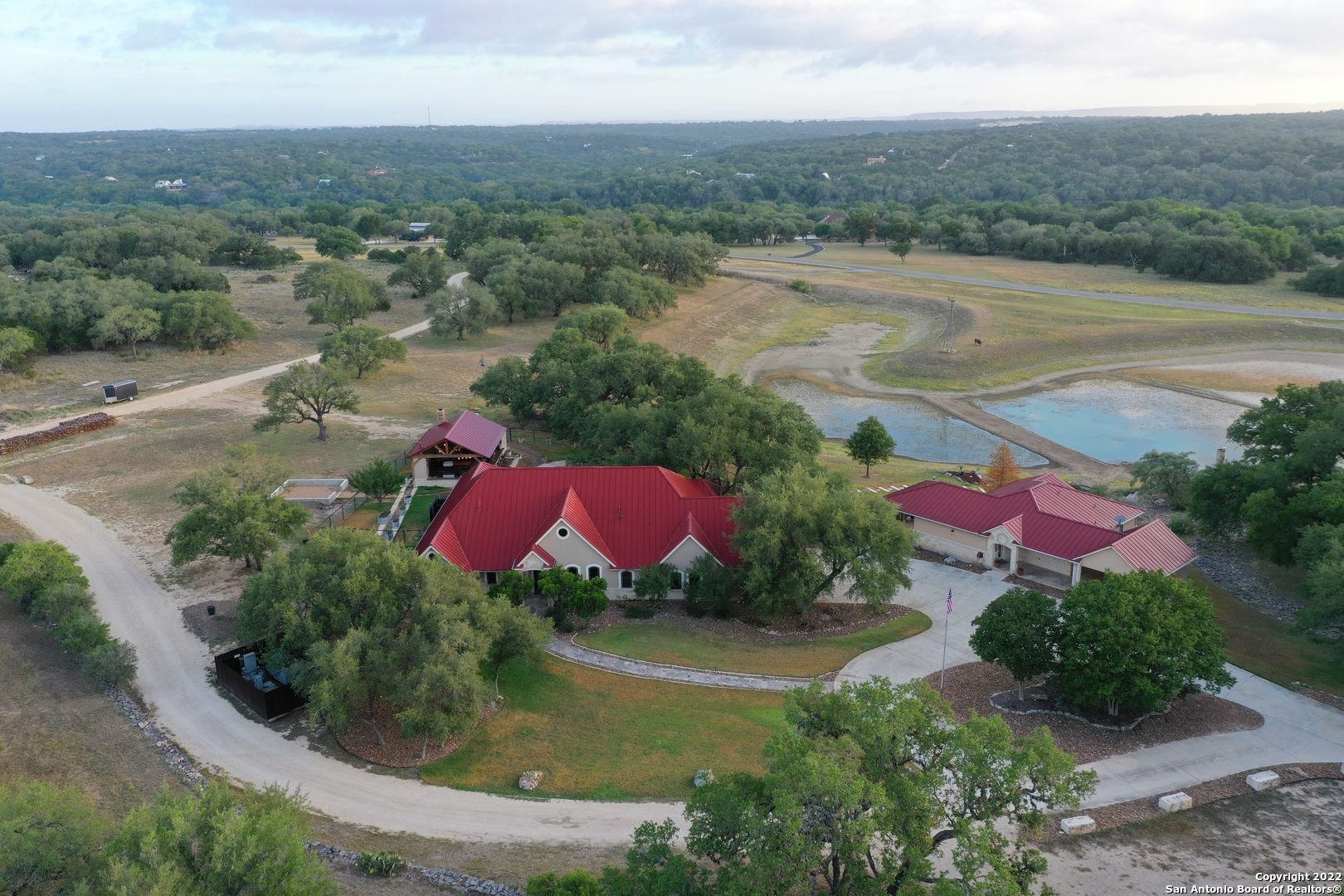 **Make sure to watch the video at https://youtu.be/KH5qi9NVqNE***  Look no further for your Texas Hill Country estate in the highly sought after gated neighborhood of Waterstone. This privately gated home is perfectly positioned between Boerne and San Antonio, just minutes from downtown Boerne.    This property is Hill country living at its finest. You will enjoy 25 oak studded acres of land, a private pond, a beautiful main house, large guest house, amazing outdoor entertainment area with a pool and spa, and an oversized  40x60 workshop with the upstairs finished out with two offices.  The main home is 3,320 square feet. The open concept floor plan has four bedrooms, three and a half  baths, a formal dining room with a wet bar, breakfast nook, large living room, and office area. The master bedroom has a sitting area and an exterior door leading to the outdoor entertaining area. His and her master bathrooms, including separate closets, vanities, and toilets, connected by a walk in shower. The second bedroom has a private bathroom, bedrooms three and four are connected by a Jack and Jill bathroom.    The newly complete guest house is 1,500 square feet. This home is fully handicap accessible with wide hallways and doorways as well as a shower and toilet area that were built for easy wheelchair access.  Two bedrooms and 2 full baths with a full kitchen, laundry room, and covered patios overlooking the property. The second bathroom is also equipped with a walk in tub. A covered two car carport is also attached to the home.  The new outdoor entertainment area is an entertainer's dream! Relax and entertain year round with this backyard oasis. The sprawling back patio includes a heated pool and spa that overlooks the property and your private pond. Pool cabana and outdoor kitchen are 1,000 square feet of pure bliss canopied by beautiful oak trees. The perfect place to take refuge in the hot Texas summer. Features of the cabana are mortise and tenon trusses, beautiful light fixtures, windmill fans, large wood burning fireplace, and  plenty of seating with a double sided bar for entertaining.  The 1/2 bath includes a sauna (could be converted into a shower) and space for an extra refrigerator.  The kitchen area boasts a copper farmhouse sink, refrigerator, gas grill, 3 gas burners, wood burning brick pizza oven, gas griddle, and ice maker.  The second outdoor entertaining area includes more seating, sink, and refrigerator.  The custom fire pit built in Breckenridge Colorado by Breck Iron Works completes the area.  The oversized workshop is complete with two built out office spaces, a storage area, and a walk in cooler! Get ready for hunting season as you can bow hunt on your own property and hang it to chill in your own walk in cooler.   Additional outdoor features include a whole house emergency generator (for main house and guest house), two 500 gallon propane tanks (buried), an additional outdoor storage building for lawn mowers, etc, and concrete footings for a greenhouse 20 x 20 - electric and water are available.  This property is a sportsman's paradise. Axis deer, whitetail deer, turkey, ducks, and cranes call this property home. It's not unusual to see 25-50 head of axis deer drinking at the pond.   Take advantage of Waterstone's two private river parks. You can put your kayak or tube in one park and float down the river to the second park. Float the river without ever leaving the comfort of your community! Enjoy country living at its finest, yet still close to San Antonio (20 minutes), Boerne (20 minutes), and Spring Branch (20 minutes). Your new homestead awaits! This property has everything you need, plus the tranquility of living in the Texas Hill Country. Don't forget you will be in the highly acclaimed Boerne Independent School District, a huge reason why people move to Boerne! And, you will be living in one of the happiest small towns in America! (Take a look at the article https://www.onlyinyourstate.com/texas/happiest-