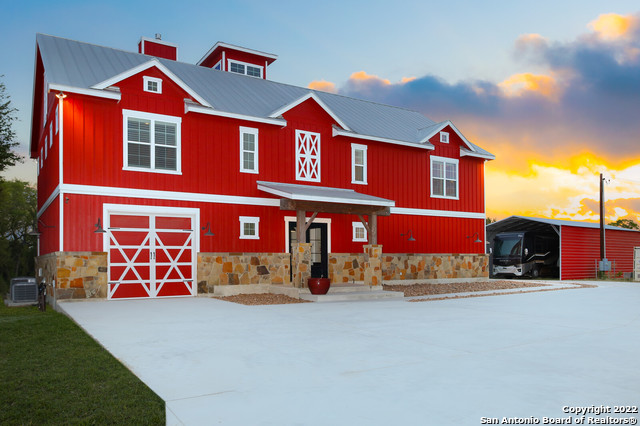 This uniquely custom home is nestled in Texas Hill Country minutes away from hwy. 281.  You can enjoy your beautiful Texas sunsets from your own balcony. This property is gated and fenced with high game fencing. A delivery drop box is located at the entrance of the property ensuring you get all your important deliveries. This home was designed to entertain downstairs with living upstairs.  But don't worry, this home also comes with an elevator to make going upstairs easy for anyone.  Downstairs you will find an amazing set up for entertainment to accommodate many guests with wet bar, sitting area, space for a pool/ping pong table, and a full bathroom. Looking out from the entertainment/game room is the oversized patio with wood burning fireplace and cooking area overlooking a custom designed pool by Keith Zar, and a putting green.   The covered patio overlooks the expansive backyard. The pool is top of the line Pebble Tech in- ground, self-filling, heated, and self-cleaning.  Turf lines the area from the patio to the pool. And enjoy some drinks while putting by the pool with your very own putting green.  There is plenty of room to entertain in and around the home.  Upstairs is your complete living space with an open floor plan, 3 bedrooms, 2 full bathrooms, a cook's kitchen open to the dining and living room.  Kitchen is located in the center of the home equipped with Thermador Appliances including a 6 burner + griddle cooktop, dual convection ovens, pot filler, warming oven, microwave/ steamer, refrigerator, walk-in pantry and much more.  The master suite includes a relaxing ensuite bath with walk in shower, freestanding soaker tub designed for two, separate vanity sinks, and direct access to the laundry room.   The master closet includes a sitting area, custom shelving/ storage, and a 3 tiered mirror to make picking that perfect outfit a breeze.  A large balcony is located off the main living space perfect for having a glass of wine while watching the beautiful Texas Hill Country sunsets.    The home is a must see to appreciate all that it offers.