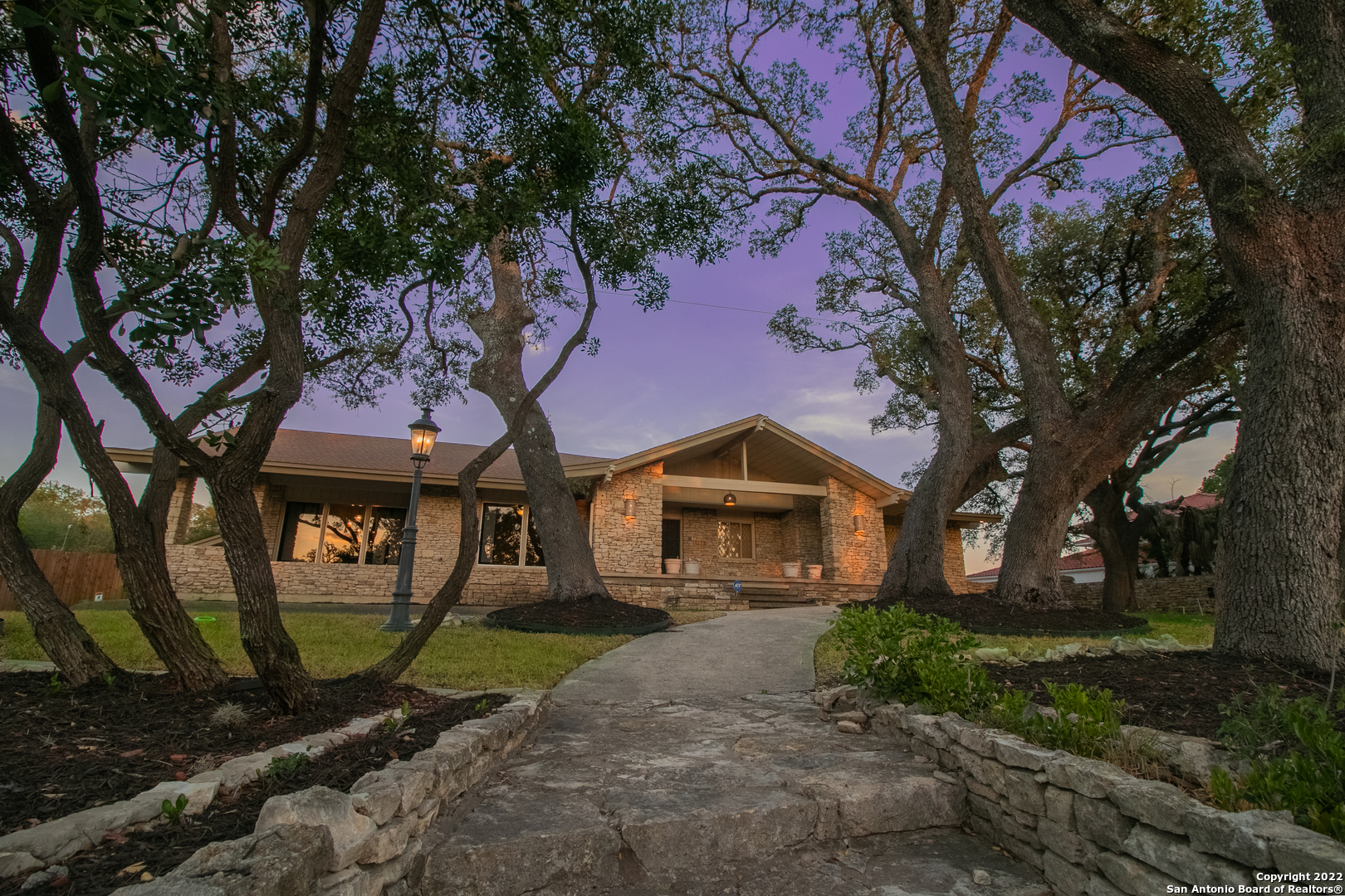 This 1.5 story stone faced home is nestled on .59 acres surrounded by mature trees & stunning views of San Antonio's skyline. This 4 bed 4 bath home, built by W. R. Craig,  has had ENDLESS amounts of recent interior updating: 5 ton A/C (Trane Home App w/two thermostats) (2019), 2 ton A/C (2019), blown-in insulation in roof/ceiling (2019), double pane energy efficient windows w/tilt inwards feature (2019), ceiling fans w/light fixtures & remote controls (2019), One Day Blinds in master w/remote & wall swtich (2019), One Day Blinds in living room & kitchen (2019), electronic entry into home thru garage w/2 remotes (2019), surround sound in living room by patio, kitchen & patio w/Onkyo app (2019), security cameras w/Night Owl app & tv monitor (2019).  Welcome through the wood double door front doors into the spacious front entry. You are meet with the front living and dining room. The family room features a stone gas fire place, attractive wooden beams & opens to the kitchen. The kitchen updates include stainless steel appliances: built-in oven (2019), gas range (2019), dishwasher (2019), built-in microwave (2019), pot filler (2022), disposal (2022). The kitchen also features granite countertops, attractive backsplash, island & breakfast bar. The spacious master retreat features a large window w/picturesque views of downtown & the pool, large walk- in closet, built in cabinetry, large vanity & walk-in shower. Great sized secondary bedrooms! The backyard is an entertainer's dream: stunning pool, HUGE covered patio w/fans, breathtaking trees surrounding the backyard. Very large driveway, plenty of room for rvs or multiple cars. Separate structure perfect for a guest house or workshop! The exterior features electronic privacy gate to driveway (2019), keypad at gate (2019), outdoor lighting along tree/fence, front & backyard, along pool & streetside (2019), 4 solar lights (2019) & blacktop driveway (2019). Large laundry room w/tons of cabinetry & two sided sink. Wonderful opportunity! Homes in this neighborhood don't come up for sale often!