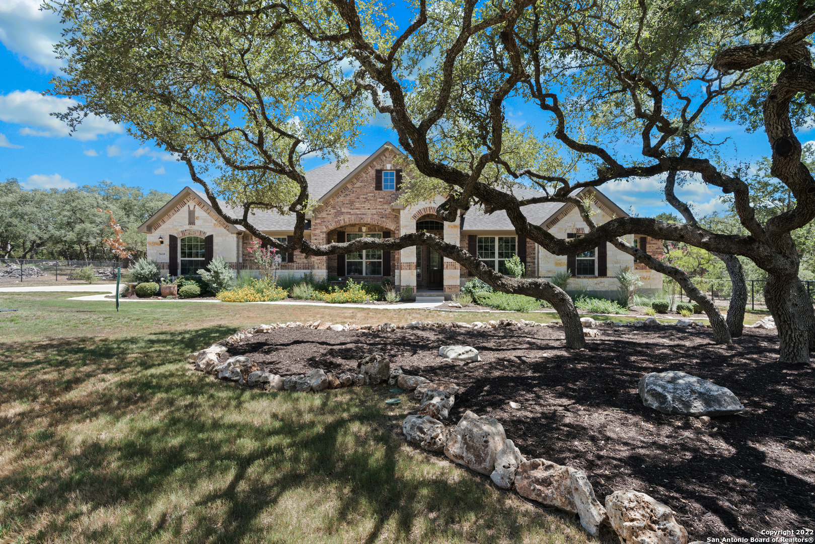 This immaculate estate is nestled amongst 40+ mature oak trees on over 1 acre with no backyard neighbors for the ultimate peace and tranquility. Meticulously maintained, this home is the essence of move-in ready. Upon arrival, guests are greeted by a manicured lawn and delicate landscaping guiding the extended driveway. Inside, the grand foyer leads to an open floor plan suitable for entertaining. The living space showcases tray ceilings and a warm fireplace surrounded by picture windows with magazine-worthy views. Plantation shutters can also be seen throughout the entire home. To the gourmet kitchen, revel in the custom cabinetry complemented by granite counters and a center island with bar seating. Above the stove, the delicate Longleaf Pine can no longer be bought and is cherished by craftsmen. Stainless steel appliances and recessed lighting complete the kitchen. The dining area offers a unique touch like no other. 100-year-old Bead Board comes from an old barn estate, like the Longleaf pine, and adds character to the home. The luxurious-sized primary suite highlights natural lighting and plantation shutters. To the spa-like en suite, bask in the extended walk-in shower with dark-tile accents and rainfall shower head. The en suite also has dual sinks and a soaking tub. The roomy walk-in closet was built with extra storage in mind! The split bedroom floor plan offers a secondary bedroom on the same side of the primary with the remaining two secondary bedrooms on the opposite side with a spacious laundry room and flex space or retreat. Outside, enjoy al fresco dining on the covered patio, overlooking the acreage ahead. Lighting can be found throughout the trees in the front lawn for visibility at night. In addition to all this home has to offer, the community offers a 24-hour guard gated community and is just 7 miles from all New Braunfels has to offer. With many community amenities including a pool, tennis court, basketball court, playground, and party pavilion, come see this property today.
