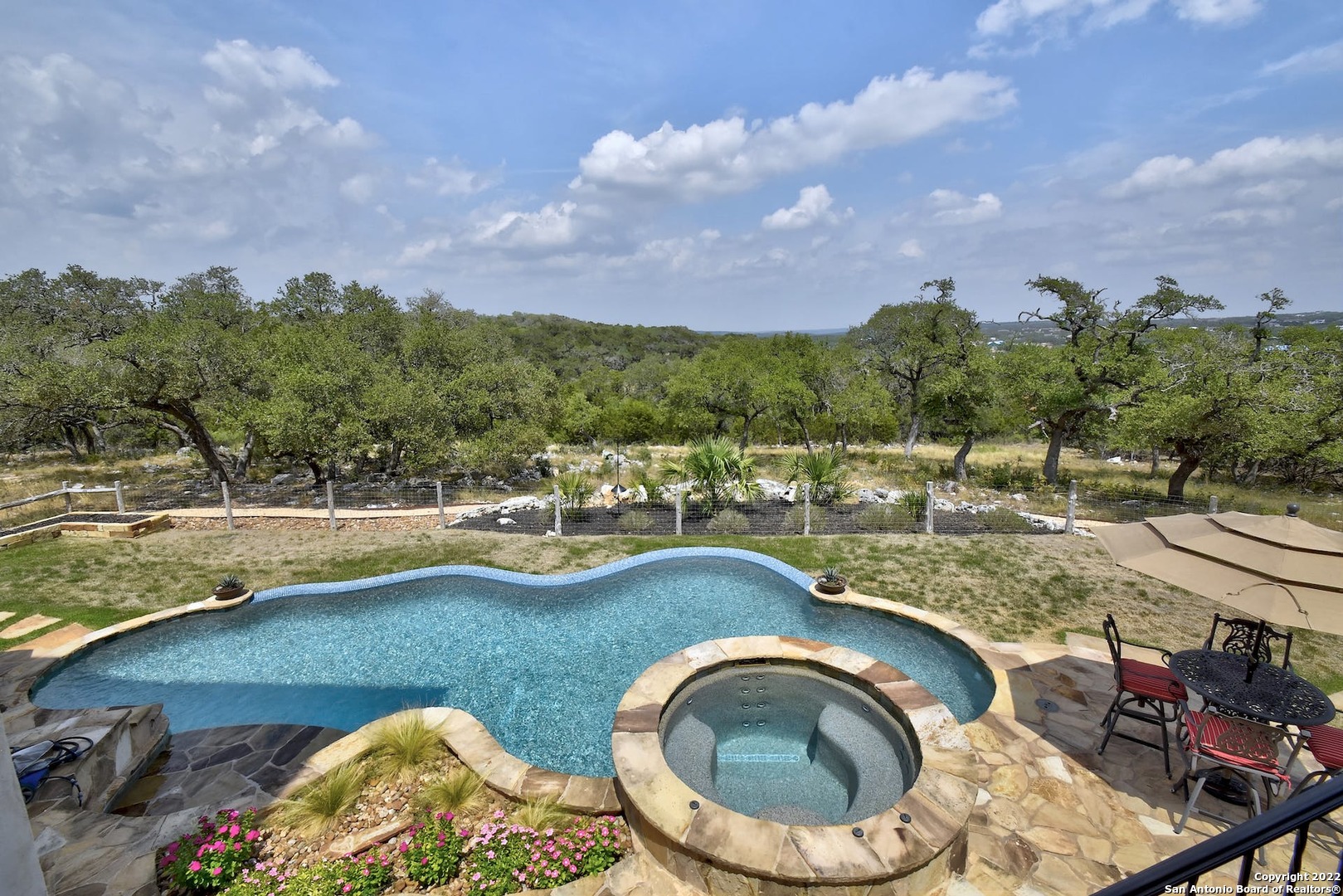 Welcome to the best of refined French Country elegance set high-atop our glorious Texas Hill Country. This magnificent River Hills Custom Home is positioned expertly on 2 picturesque acres so each room is graced with views that never end. This home's design strikes a balance between beauty and comfort with its intentional use of natural materials - exposed wood beams, grand stone fireplaces, decorative brick walls, plantation shutters, handmade wrought iron railings and expert craftmanship that is seen throughout this open concept floor plan. As soon as you enter you will be greeted by the stunning views through 6 sets of French Doors and floor to ceiling windows where the natural light streams in to your primary living area featuring 25 ft soaring ceilings accented with a soft neutral palette. This 4 Bedroom/5 Bath home was thoughtfully built so that you and your guests would have a wonderful experience every minute of every day - A wine cellar with storage for over 200 bottles of your favorite vintages, a guest/mother-in-law suite that has a sitting area/kitchenette and ensuite bath with a dual sided, glass fireplace and a separate, private entrance; the Master Suite was created for your ultimate comfort featuring access to an outdoor, 50 foot long covered patio, a coffee/beverage bar, a master closet with an oversized, built-in dresser, shelves for the ultimate storage and a make-up vanity so your daily routine is made easy. And, tucked away in the suite is a secluded Exercise Room that could also be used as a 2nd Office, Studio or Nursery.   When you walk up the exquisite wooden, spiral stairs you will find a fun filled game room with enough space to enjoy playing or watching your games - pool, poker, football or basketball with a full wet bar for you and your guests to enjoy. This floor has 2 additional generously sized bedrooms - one with an ensuite and the 4th bedroom that is currently being used as a media room.  Of course, you'll  want to extend your entertaining to the outside  where you'll love how easy it is to spend hours grilling your favorites in the outdoor kitchen, swimming in the cool, sparkling pool or relaxing in the heated spa.   With the very best views in the entire neighborhood, once you step inside this Hill Country Masterpiece, you will never want to leave.