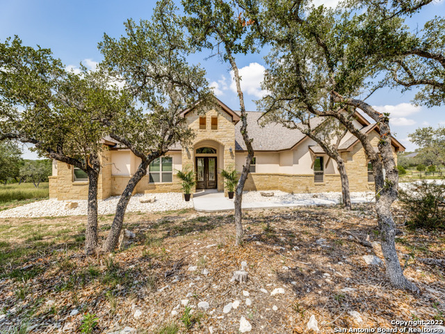 Come home to your own slice of Texas in the prestigious gated community of Cascada at Canyon Lake. Fabulous new custom build located in one of the most fantastically beautiful parts of the Texas Hill Country with natural springs, palmettos, Spanish beard moss, and magnificent Texas live oaks. One of the clearest lakes in Texas is just down the road, a private river park offers kayak storage and lake access via Rebecca Creek for residents, Fern Canyon Preserve hiking trail and great neighbors add to the experience of hill country living at its best. In addition to majestic oaks and panoramic views throughout the area, you'll enjoy casual elegance with an ideal luxury floor plan that brings the outdoors inside.  This gorgeous single level home was completed in December by an excellent builder and has barely been lived in. Ideally situated with the back of the property terminating into Fern Canyon means no neighbors behind to spoil the view. This gorgeous offering with flowing spacious design, clean lines, elevated ceilings treatments, and neutral palate offers luxury and livability. You will adore the tranquility and calming view  from the windows. From the front entry gaze right through to the outdoor living area and back acreage.  The kitchen boasts gorgeous white quartz counters, double islands, stainless appliances, double oven and recessed, pendant & under cabinet lighting. Relax in a stunning primary retreat with dual vanity sinks, make up vanity, counter to ceiling mirrors, soaking tub and walk in shower along with dual walk in closets.  Guest suites are joined by a jack n jill bath while the flex room is perfect for an enclosed study or den. The outdoor living space looks out over  a grove of oaks on your own acreage. A DEEP and oversized 3 car garage with side entry is just what you need. Yes, an F-350 will fit with no issues so bring your SUVs and rec vehicles. Plus, you have the option of storing additional river gear at the private river park storage where Rebecca Creek joins the Guadalupe River providing kayak access to Canyon Lake. Boat ramp #1 on the river is 8 minutes away and Potters Creek boat ramp is 12 minutes away. The marina is 16 minutes.  In a sister unit,  well appointed casitas with views can be rented by extended stay guests.  With an absolutely gorgeous setting of canyons and ridges, Cascada is bordered by a private ranch.  A gorgeous wedding venue is also located in a neighboring unit. Cascada unit 1 is gated on both sides of the community, keeping it gloriously private and quiet.  Come visit this incredibly beautiful part of Texas and you'll see why so many who are introduced to the unspoiled beauty of Cascada decide to stay.