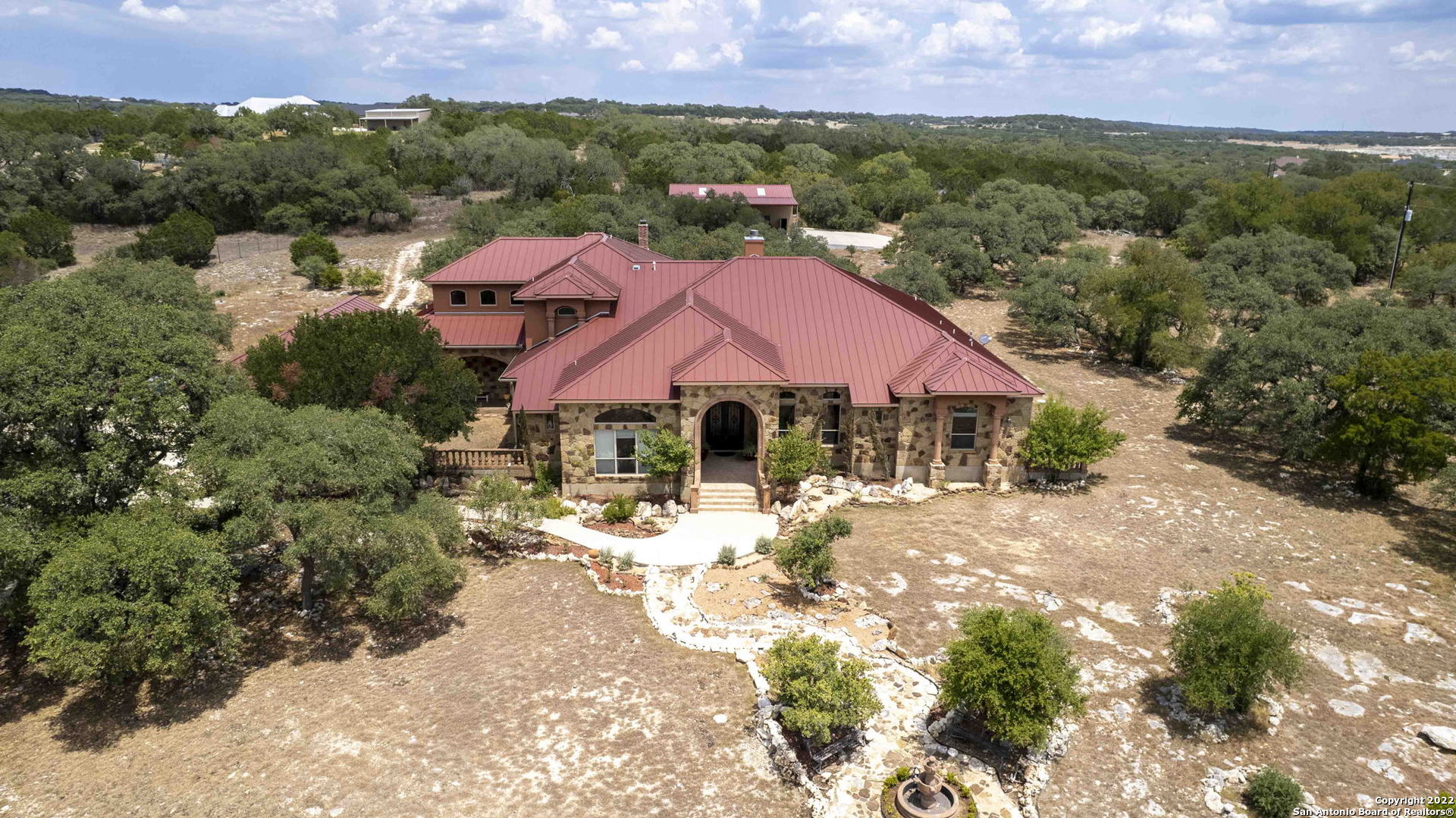 Gorgeous Hill Country Home sitting on 6 acres with plenty of space for entertaining or just enjoying the surroundings. Home has 5 large bedroom suites, Media room, Bar Room, Large Patio with outdoor kitchen for BBQing and making homemade pizza. The kitchen is a Cooks dream with an oversized pantry, large island, 2 vegetable sinks, and an open concept. 2 Ice Makers and 2 Beverage Refrigerators so that you never run out of a cold drink. Listen to music from every room in the house with Surround Sound. 4K projector in Media has been recently purchased. Two entrances to a 50ft by 30ft RV Barn in the back so you never have to back up the RV. The Barn is equipped with RV connections, Full bath, 2 large Chain Link Garage Door Openers, Sun Lit roof, and a 50ft by 20ft Covered Patio and fenced. The community has access to Canyon Lake and a boat ramp. The community also offers many amenities from club house, basketball court, volleyball, jogging trails, and much more.