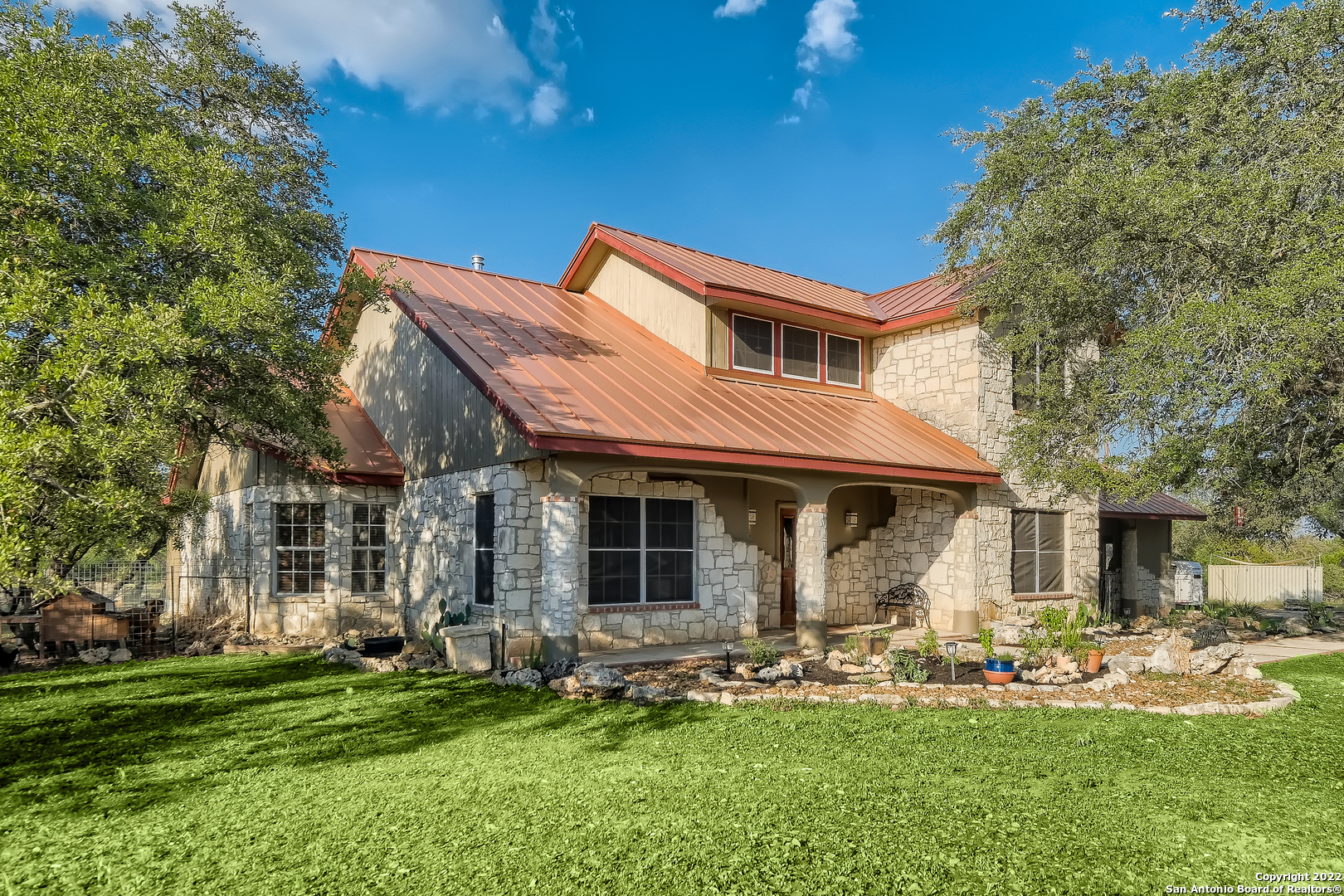 Come live your best life in Spring Branch on this unique 5-acre gated farm property conveniently tucked off Hwy 281 with no known restrictions, no city taxes, and no HOA!  Custom home built in 1993 with 4 bedrooms and 2.5 baths. The character and charm include masonry accented walls, farmhouse kitchen, hardwood floors, rustic finishes including a wood-burning fireplace, metal, and wood ceiling in the living area, and antique Spanish style Mission Shudder doors that open to the scenic views and back pasture.    Downstairs you'll find the spacious primary bedroom suite with two closets and two vanities. Enjoy picturesque views overlooking the organic Victory garden, fire pit, and horse pasture while soaking in your large tub. Currently, an executive home office could serve as a second bedroom. The kitchen, dining room, and living area are spacious and open into a vaulted ceiling. Upstairs are two additional bedrooms with a full bathroom. Watch Texas sunsets and falling stars next to the large firepit in the yard that overlooks beautiful views of surrounding Hill Country.     Upgrades completed in the past two years include a fully enclosed 7 ft deer fence with 3 strands of top wire for the entire property, new standing seam metal roof, GVTC High-Speed internet, Bosch dishwasher, masonry work, electrical upgrades for light fixtures, in-air duct UV light purification system for HVAC, new fireplace with chimney, driveway completed with new stonework and fully landscaped.    This farmette offers a variety of fruit trees including 3 persimmons, 4 figs, 4 peaches, a plum, lemon, and key lime, all planted by the current owner. The owner is a member of the American Rose Society and has over a dozen drought and disease-tolerant varieties of roses including David Austin roses.     Looking for a spot for all creatures great and small? Bring your horses to enjoy a George Strait sand riding arena, separate metal fenced stud area, plus there is plenty of room for dogs, chickens, goats, a pool, a barn, and whatever your desires might be.