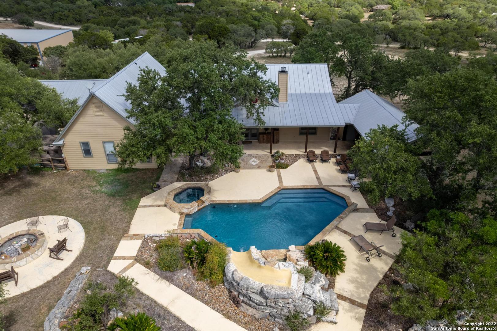 28.70 acres, ag exempt w/3348 Ft2 3 bed, 3.5 bath 1.5 story home. Exterior of home boasts outdoor kitchen/cabana area, gorgeous pool with waterfall, slide & adjoining hot tub. 26x26 attached carport, 40x40 detach garage, 41x25 pole barn, chicken coop/stalls, & 5500 ft2 metal bldg operating as a gym leased until June 15, 2023. Solar installed in 2022. All bedrooms dn. Loft w/closet & full bath up that could be a 4th bedroom. Open kitchen to family room featuring stainless steel appliances, granite counters & stone accents on bar & fireplace. Jack n Jill bath between secondary bedrooms, primary suite dn w/on suite bath offering dbl vanity sinks, whirlpool tub & sep shower. Easy access to Hwy 281 and SH 46, less than 30 mins to Canyon Lake and Spring Branch.
