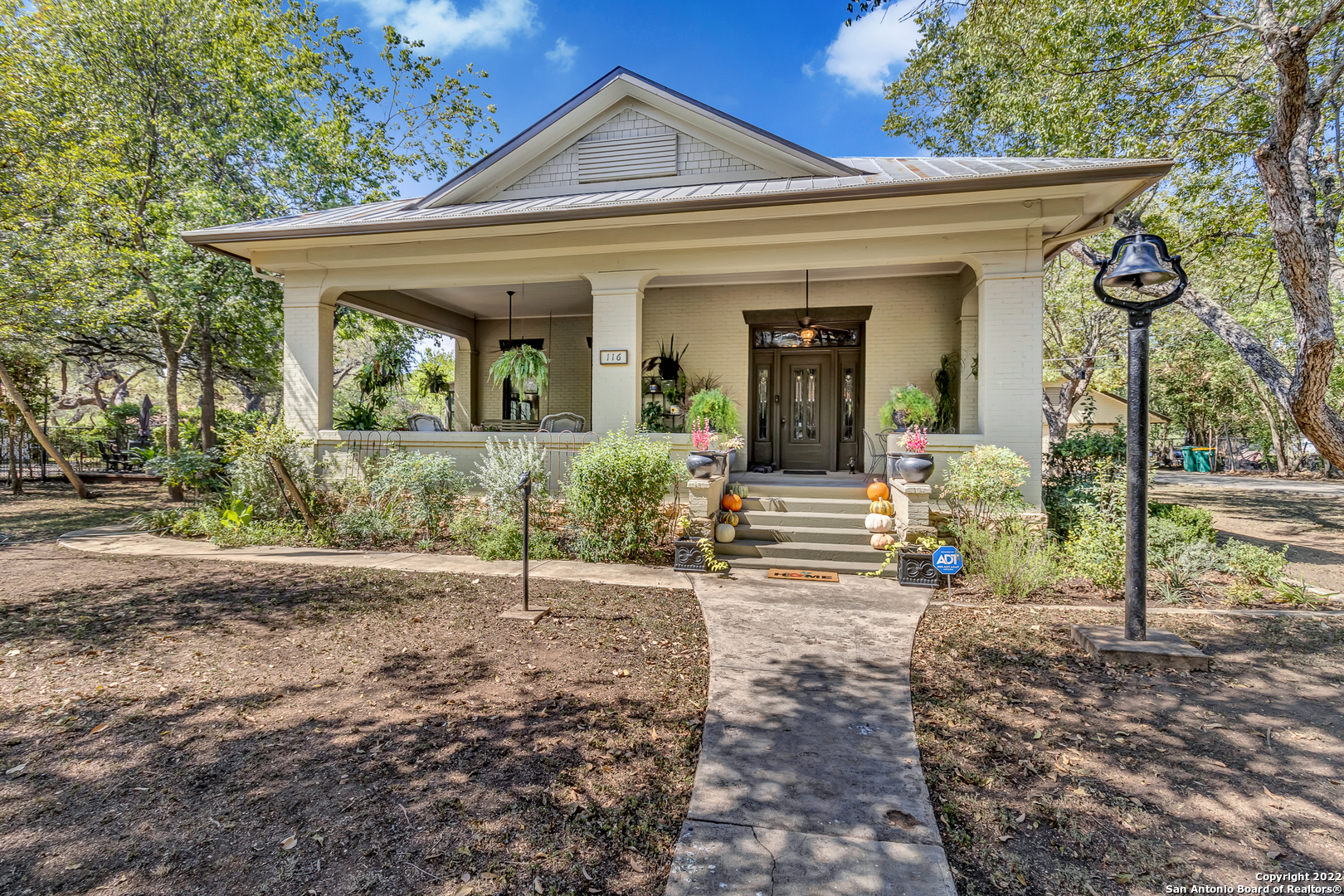 Premiere location in downtown Boerne! This home has the perfect southern living porch to gather with family & friends. If you love timeless charm & tons of character, then you have to see this beautiful, 1914 Craftsman bungalow just a block from River Road. It features architectural details galore and is an absolute favorite of locals and tourists alike. The original Ebensberger home sits elegantly behind a gated, wrought iron fence with a detailed finial post design. For fans of the beloved Arts & Crafts homes, you will find all the expected offerings, including wood-beamed, grid-paneled ceilings, warm wood floors, and an earthy, river stone fireplace with an extended, craftsman mantel. Notice the intricate newel post, gorgeous pocket doors that separate the living and dining, and the classic stained glass entry door, sidelights, and featured transom windows. The layout of this amazing historic home lends itself to flexible styling and livability as a one or one-and-a-half-story. The owner's suite and secondary bedroom are both on the first floor, as well as a full bath with black and white, hexagon mosaic tile, claw foot tub, pedestal sink, and original built-in mirrored cabinet. There is an air-conditioned sleeping porch just off the second bedroom, plus a den/library/office at the back of the house with bookshelves that flank the entire wall and look over the pool and backyard. The charming kitchen has maintained the bungalow's integrity with old-world custom cabinets, see-through glass fronts, and a copper farm sink. Included in the square footage is approximately 530 sq. ft. in the finished attic. It could be used as a potential third/fourth bedroom, game room, or a perfect getaway space for guests with its cozy wood stove and full bath. Great potential here also for a Bed and Breakfast or possible short-term rental. This historic estate home is just one long block from River Road, Cibolo Creek, walking trails, and ducks by the dozen. Enjoy Boerne's live music, restaurants, and shopping galore, just a short distance from your relaxing front porch. If you love entertaining, lounging by the pool, food with friends, and parties in the cabana, check this one out. Also has a great 3/4 car garage/workshop, and greenhouse. There's something here for everyone.