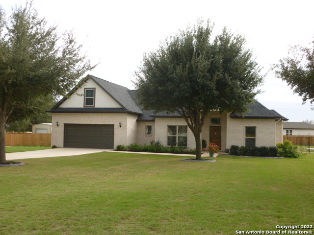 Come to Lytle for that small town lifestyle and yet close to the big city. This custom-built home has lots of space. Featuring quality construction with an open floor plan, high custom ceilings, wood look plank tile flooring in the living areas, corner living room fireplace, granite countertops throughout, breakfast bar, with a barrel ceiling in the kitchen, spacious walk-in pantry, stainless appliances and custom cabinetry. The split master suite boasts a huge walk-in custom closet, large garden tub and glassed-in shower with his/her separate vanities. Upstairs you will find a larger living space to use for whatever your heart desires in this wonderful space. Need not to forget take off your shoes in the small space dedicated for just that right as you enter through the garage door and next to the roomy utility area with a granite counter. Outside the pretty landscaped yard has custom built flower beds, full sprinkler system, a small cement slab and extra water lines in the back for a garden. The yard is surrounded by a tailor-made rod iron fence with easy access to the back and garage. Oh, also let me tell you about the separate garage/workshop that matches the home with its own drive. It has a 9ft garage door with opener, overhead storage, and a 220 plug. I still have not listed all the amenities, so come take a tour of this unbeatable custom home before it's too late to make it yours.