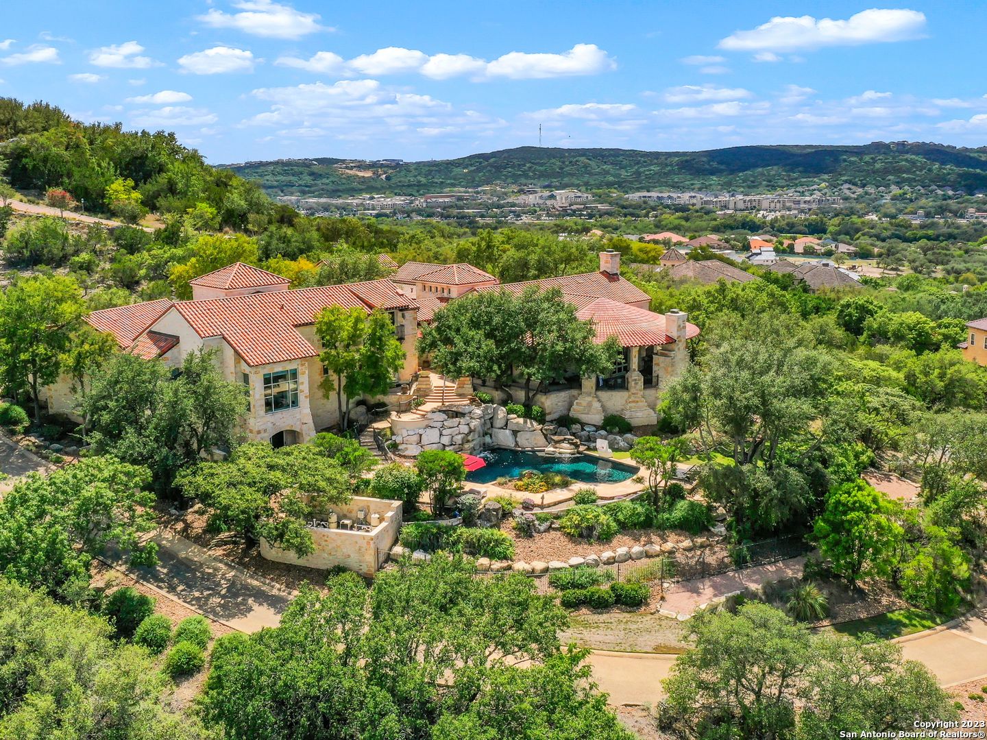 Unparalleled craftsmanship! Located on a 2.35+- acre hillside lot this perfectly situated home relishes the awe inspiring 180+ degree Texas Hill Country views from every room! This architecturally significant Dominion home is one-of-a-kind, and was designed by renowned architect, Roy Braswell, and built by master builder, Image Custom Homes. The finest appointments throughout are fit for the most discerning buyer. Grandeur open living space is appointed with vaulted ceiling, floor to ceiling stone fireplace and opens to dining room with doors opening to expansive covered patio. Entertainers dream kitchen with Sub Zero appliances, custom cabinetry, and large center island with breakfast bar, is adjoined by wet bar and separate caterers' kitchen with extensive storage and secondary dishwasher. Primary suite offers outdoor access with its own covered patio and generous ensuite bath boasting natural stone elements, multiple vanities, built-ins, two closets, and soaking tub overlooking serene private yard. 3 secondary bedrooms are on the first floor, each with their own ensuite bath and breathtaking views. Spiral staircase leads down to entertainment level with game room, bar, full bath, and pool access. Impressive deep-water Keith Zars pool offers spa, multiple water features, diving ledge, and pristine flagstone decking providing ample poolside living space. Private drive, motor court, and three car garage provide ample room for all your toys.